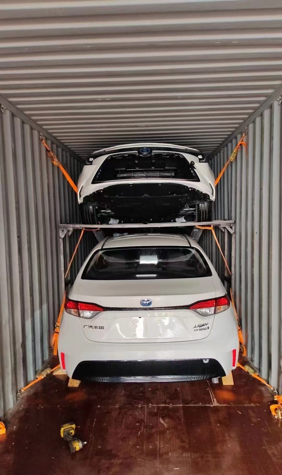 Two vehicles stacked and strapped in one container
